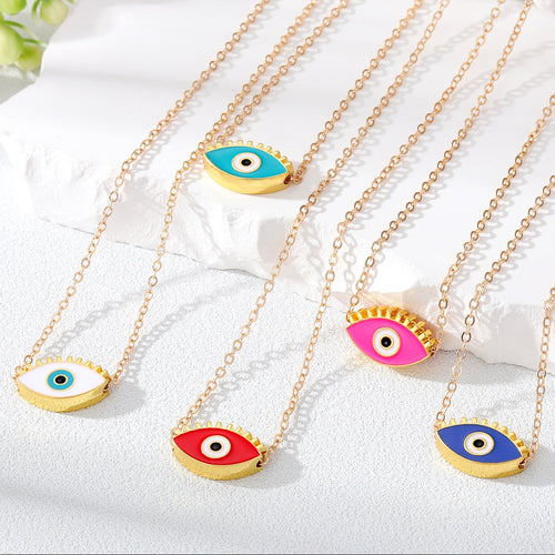Gold necklaces with colorful eye pendants on a white fabric background